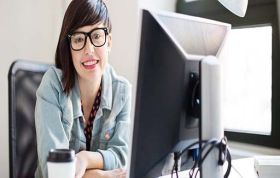 Woman with glasses focused on her computer at a desk, representing the MCSA SQL Server 2012 Training Bundle course for database skills.