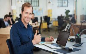 Employee with laptop seated near coworkers at separate table, representing MCSE Data Management and Analytics Online Course.