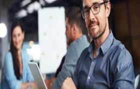 Man with glasses engaged with his laptop at a table, representing the Microsoft Designing and Implementing Windows Server 2012 Online course.
