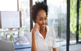 Confident female employee smiling at PC table, representing Microsoft Excel 2016 course for data and spreadsheet skills.