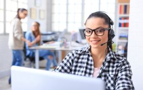 Woman with glasses and headset using her laptop, focused on tasks, representing the Microsoft Exchange Server & SharePoint Training Bundle