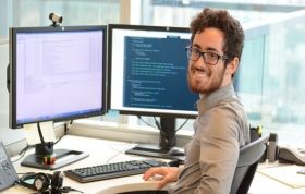 A man sits at a desk, focused on two monitors, representing the Microsoft Identity in Windows Server 2016 Online course.