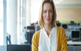 Confident female employee at office desk, representing Microsoft Implementing Data Models and Reports with SQL Server course.