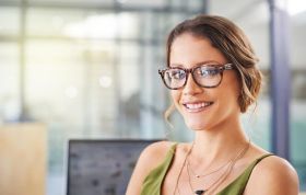 Woman with glasses smiling at the camera, representing the Microsoft PowerPoint 2013 course for enhancing presentation skills.