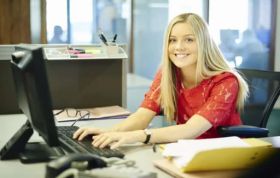 Woman focused on her computer screen at a desk, representing the Microsoft PowerPoint 2016 course for mastering presentation skills.