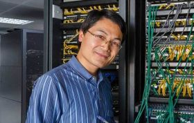 Employee standing in front of electric circuit board, representing Network Engineer Bundle course for IT infrastructure skills.