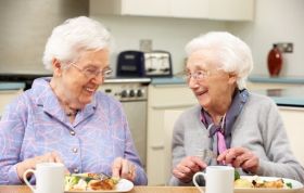 Two elderly women happily enjoying a meal, highlighting Nutrition Awareness and the ability to consume food and drink by mouth.