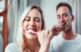 Man and woman brushing teeth in bathroom, highlighting Oral Care for Adults and the importance of mouth care in daily routines.
