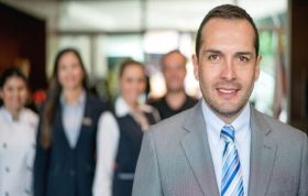 Man in suit and tie stands confidently before group, representing the PMP Online Course for project management training and certification prep.