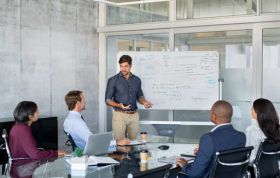 Man giving a presentation to colleagues, showcasing Presentation Skills and effective techniques for sharing data clearly.