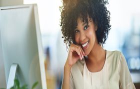 Smiling woman with curly hair radiating happiness, representing the QuickBooks Point of Sale course for retail management and transaction skills.