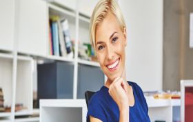 Cheerful woman seated at desk, suggesting a positive work environment, representing the QuickBooks course for accounting and financial management skills.