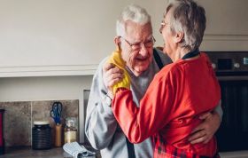 Older couple embraces in a cozy kitchen, symbolizing the Reablement Online course focused on supporting independent living.