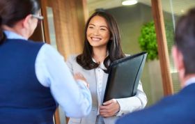 Two women in business attire shake hands, symbolizing partnership for the Recruiting Winners Online course.