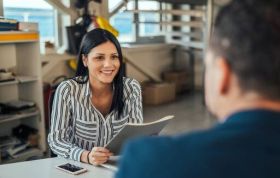 Woman handing a file during an interview, representing Right to Work in the UK and legal checks in recruitment of new employees.