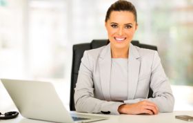 A woman in a business suit works on a laptop at a desk, representing the Risk Management Professional (RMP®) online course.