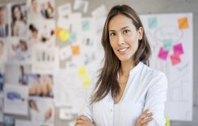 Smiling woman standing by whiteboard, representing Sage Computerised Accounting Level 1 Course for beginners.