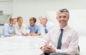 Smiling businessman in a meeting, engaged in discussion with colleagues, representing the Skillsfirst Award in Computerised Sage Business Cloud Payroll for Business (Level 1).