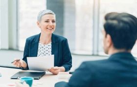 A woman speaks to a man during a meeting, representing the Staff Appraisal Online Course, emphasizing professional discussions.