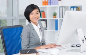 Well-dressed woman focused on her work at a desk, representing the Ultimate Microsoft Office course for mastering office skills.