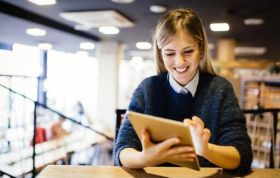 Woman focused on her tablet with a thoughtful expression, representing the Ultimate Online Marketing Bundle course for digital success.