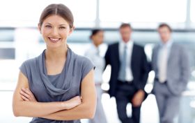 A woman stands confidently before a group, engaging them in a presentation, representing the Windows 7 Enterprise Desktop Support Technician Online course.